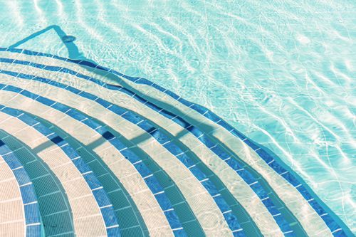 Blue and white tiled pool steps leading to a spa area, styled for a relaxing summer experience.
