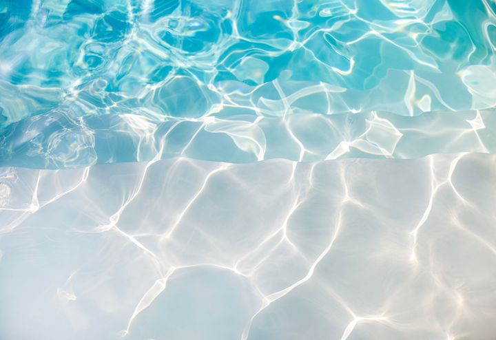 Sunlight reflecting on the clear blue water surface of a swimming pool. Sunlight reflecting on the clear blue water surface of a swimming pool.