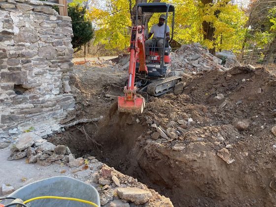 A man is driving an excavator in a hole in the ground.