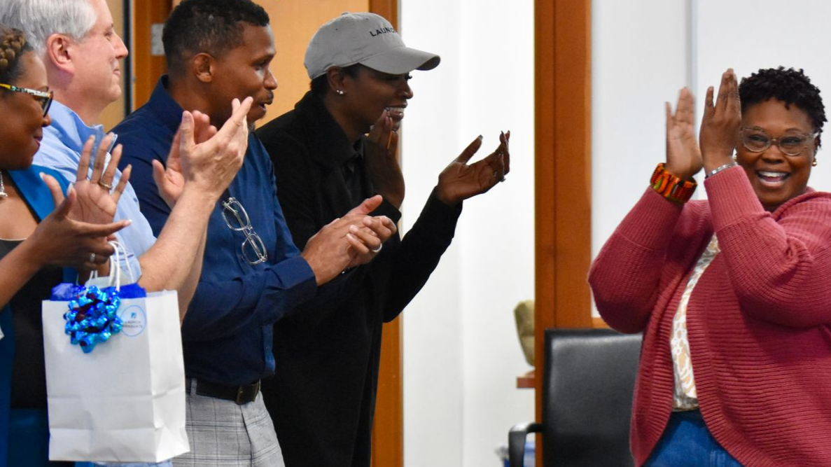 Woman in sweater clapping as team cheers are own at graduation
