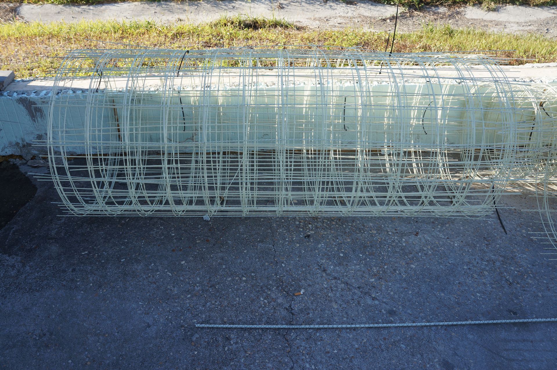 Reinforcing fiberglass cage for concrete construction, resting on pavement.