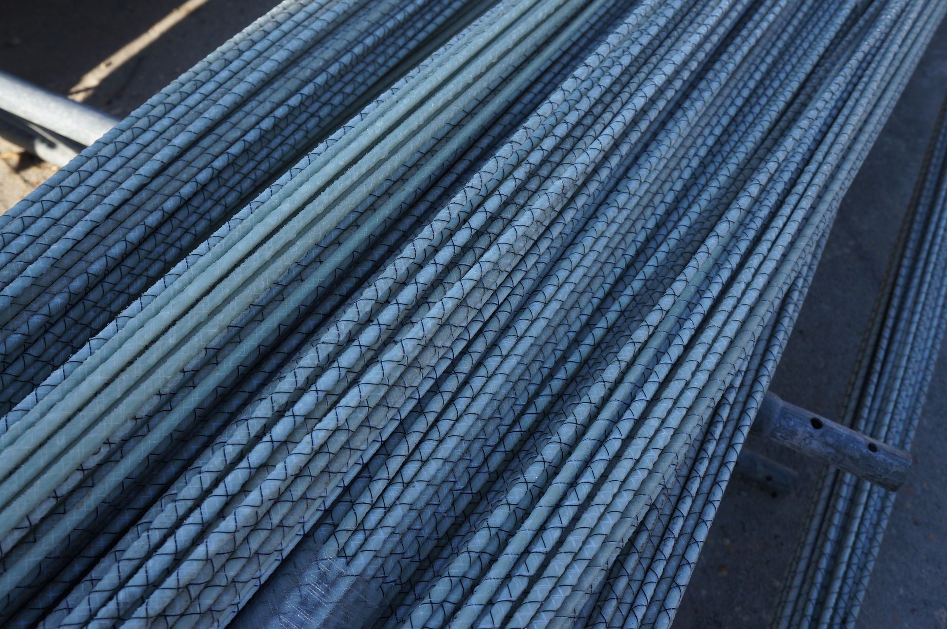 Bundle of long, gray fiberglass rods with dark cross-hatch markings.