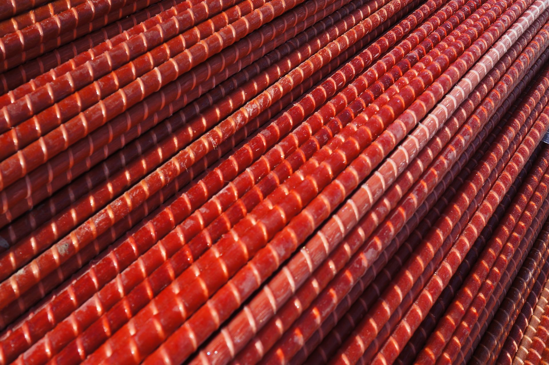 Red fiberglass rebar rods stacked in diagonal rows.