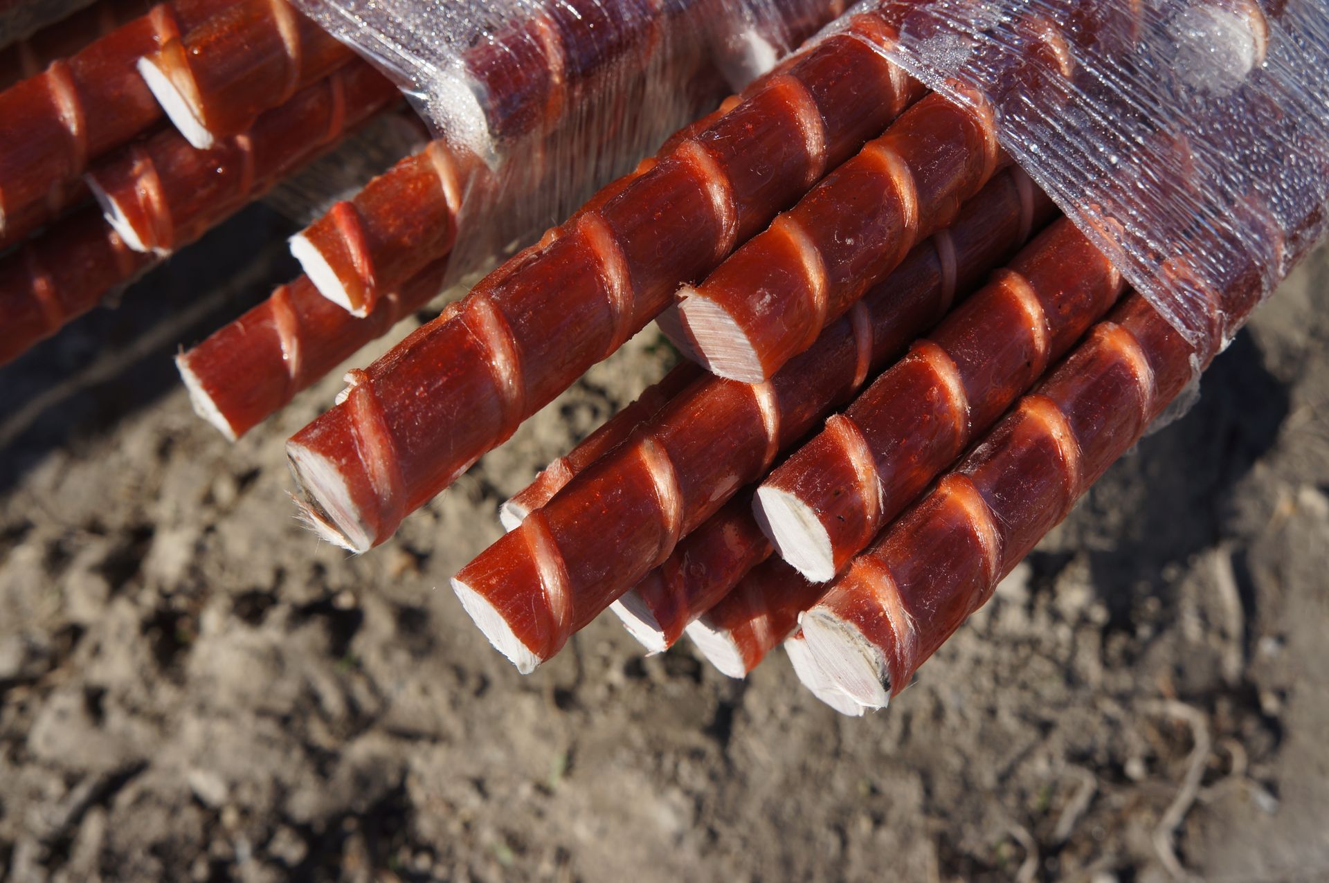 Bundled, spiraled, reddish-brown and white rods, wrapped in clear plastic, resting on a gray surface.