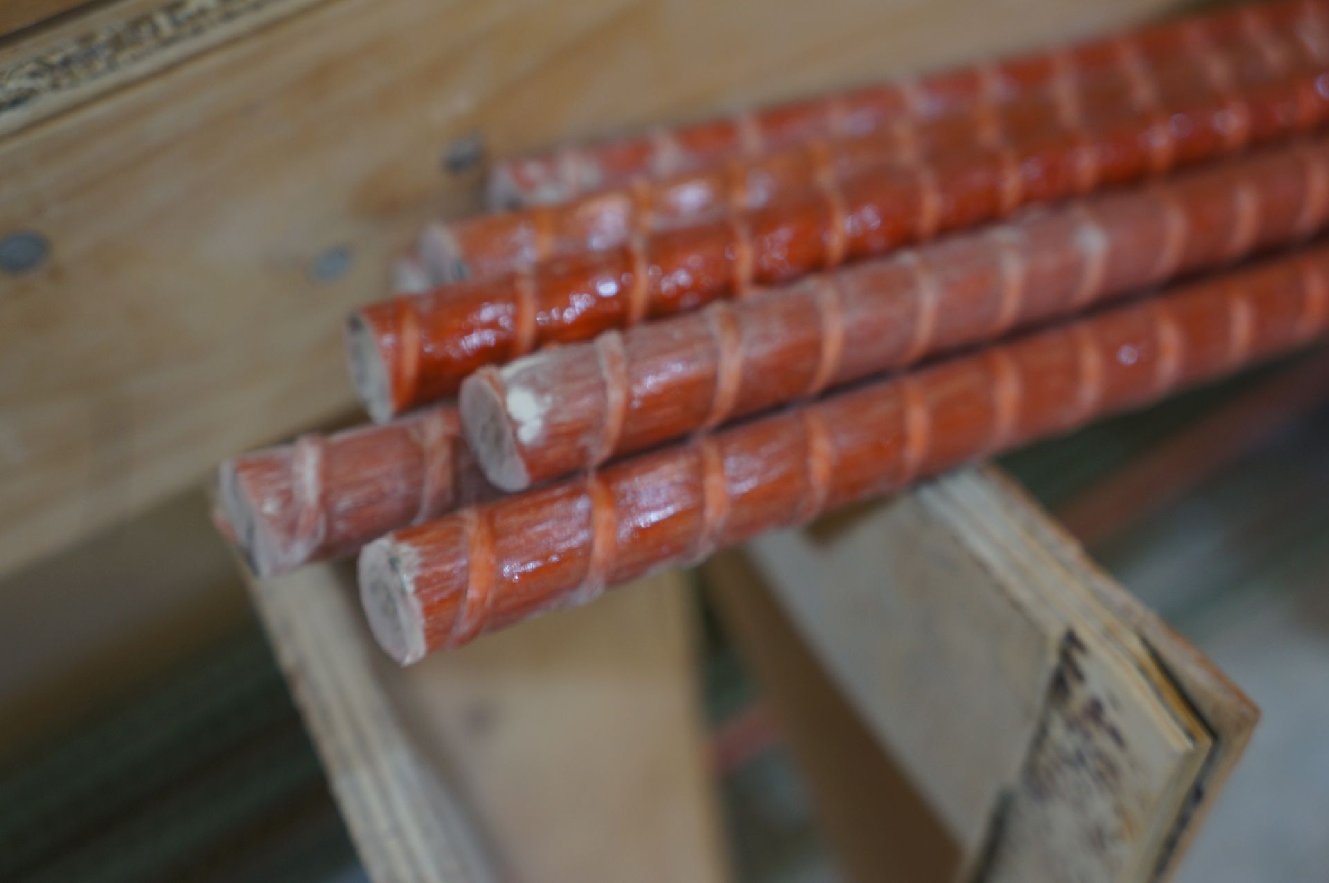 Orange fiberglass rebar rods stacked on wooden supports.