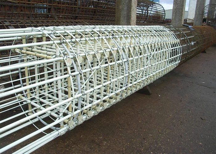 Reinforced concrete pillar cage on a wet concrete surface.