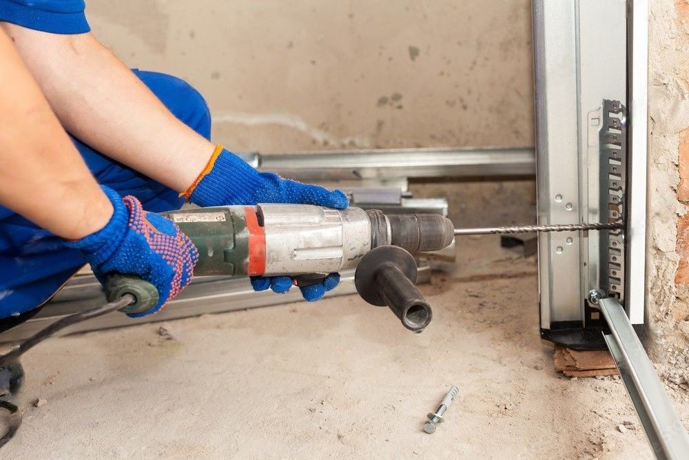 A man is using a drill to fix a garage door.