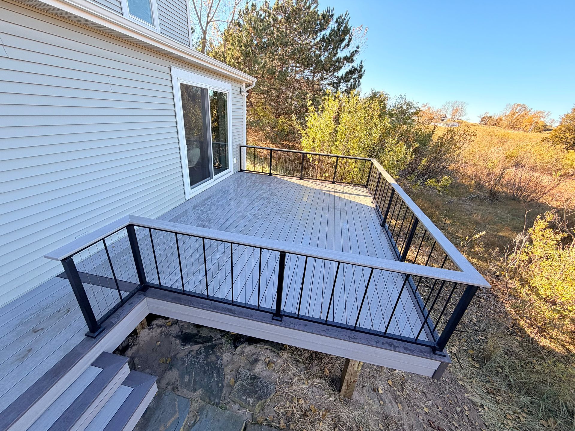 A two tone TimberTech deck featuring black Westbury Verti-cable railing along with a matching drink rail.