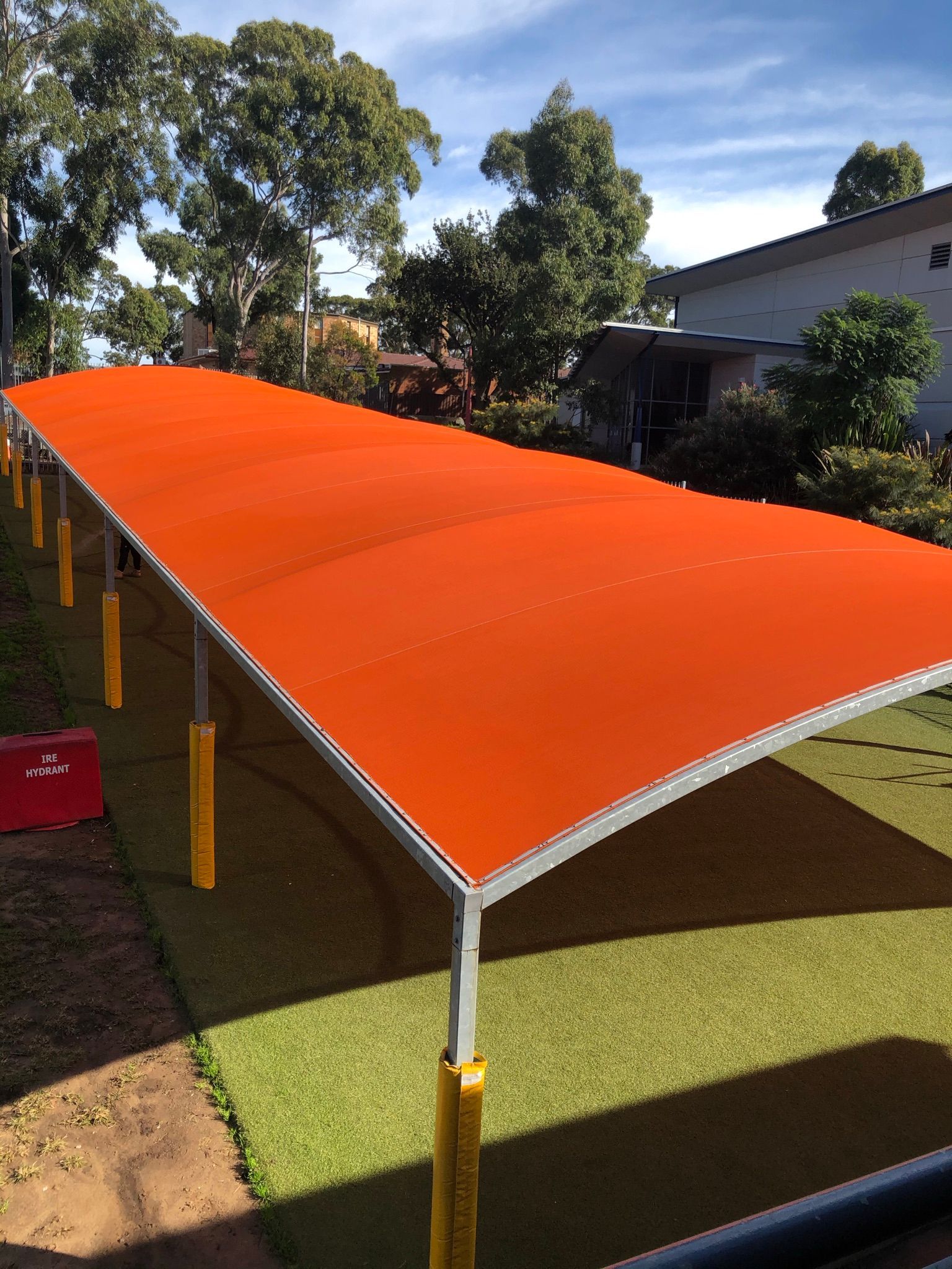 An orange canopy is sitting on top of a lush green field