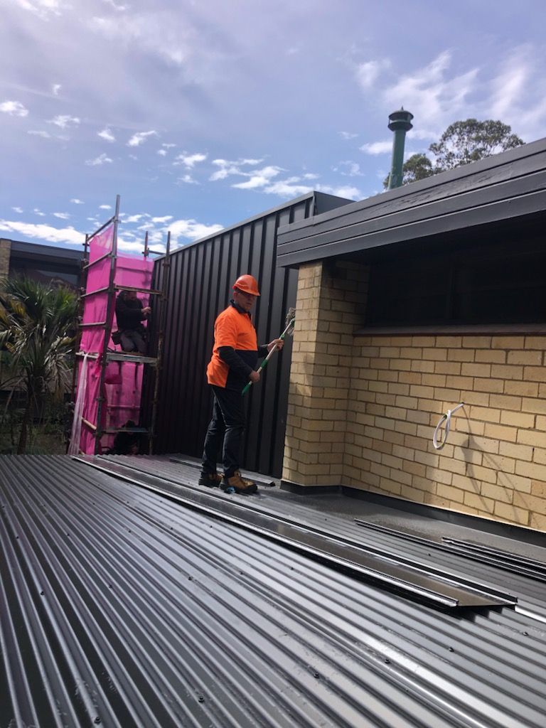 A man is standing on top of a metal roof.