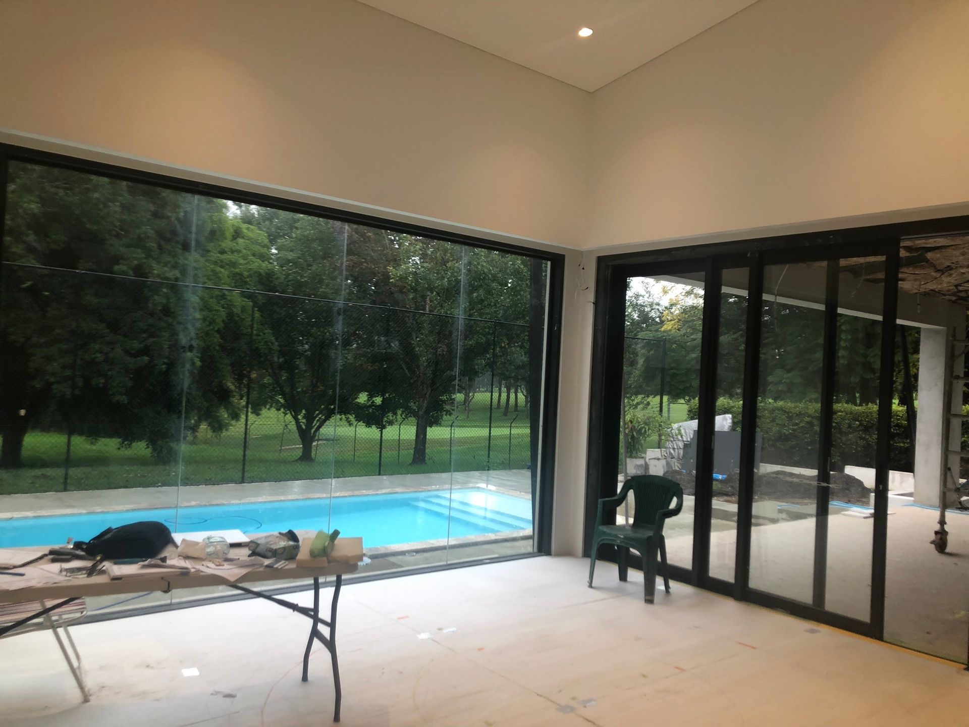 A room with a table and chairs and a swimming pool in the background