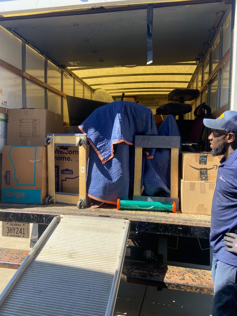 A man is standing in front of a moving truck filled with boxes.