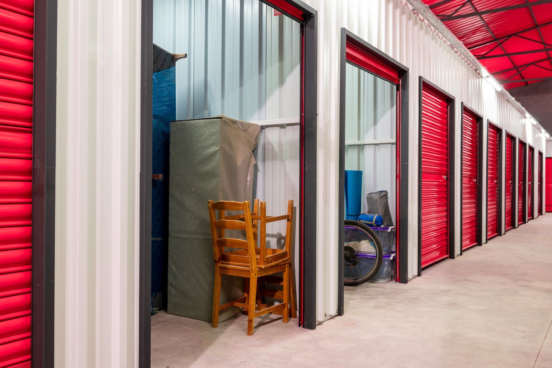 A row of storage units with red doors and a chair in one of them.