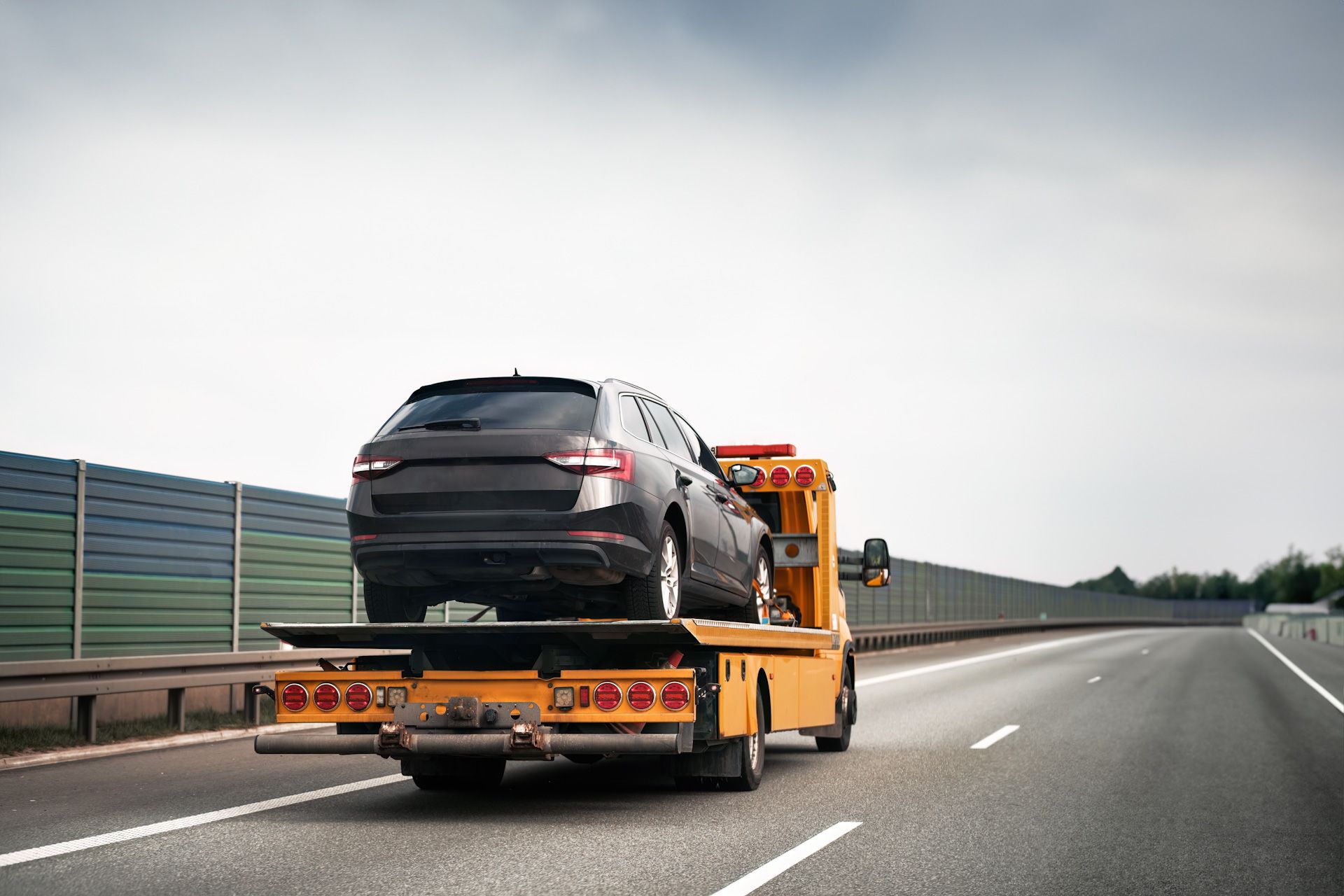 A tow truck is towing a car on the highway.