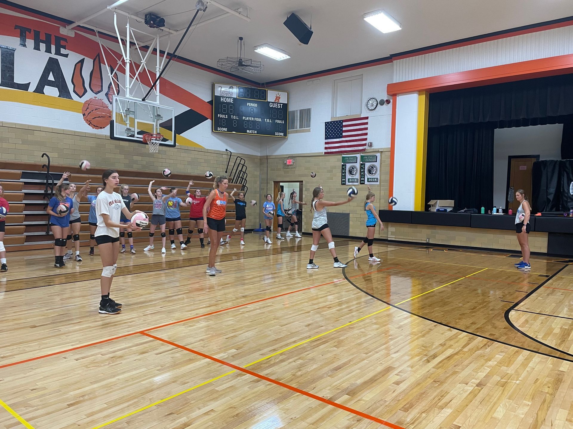 A group of girls are playing volleyball in a gym.
