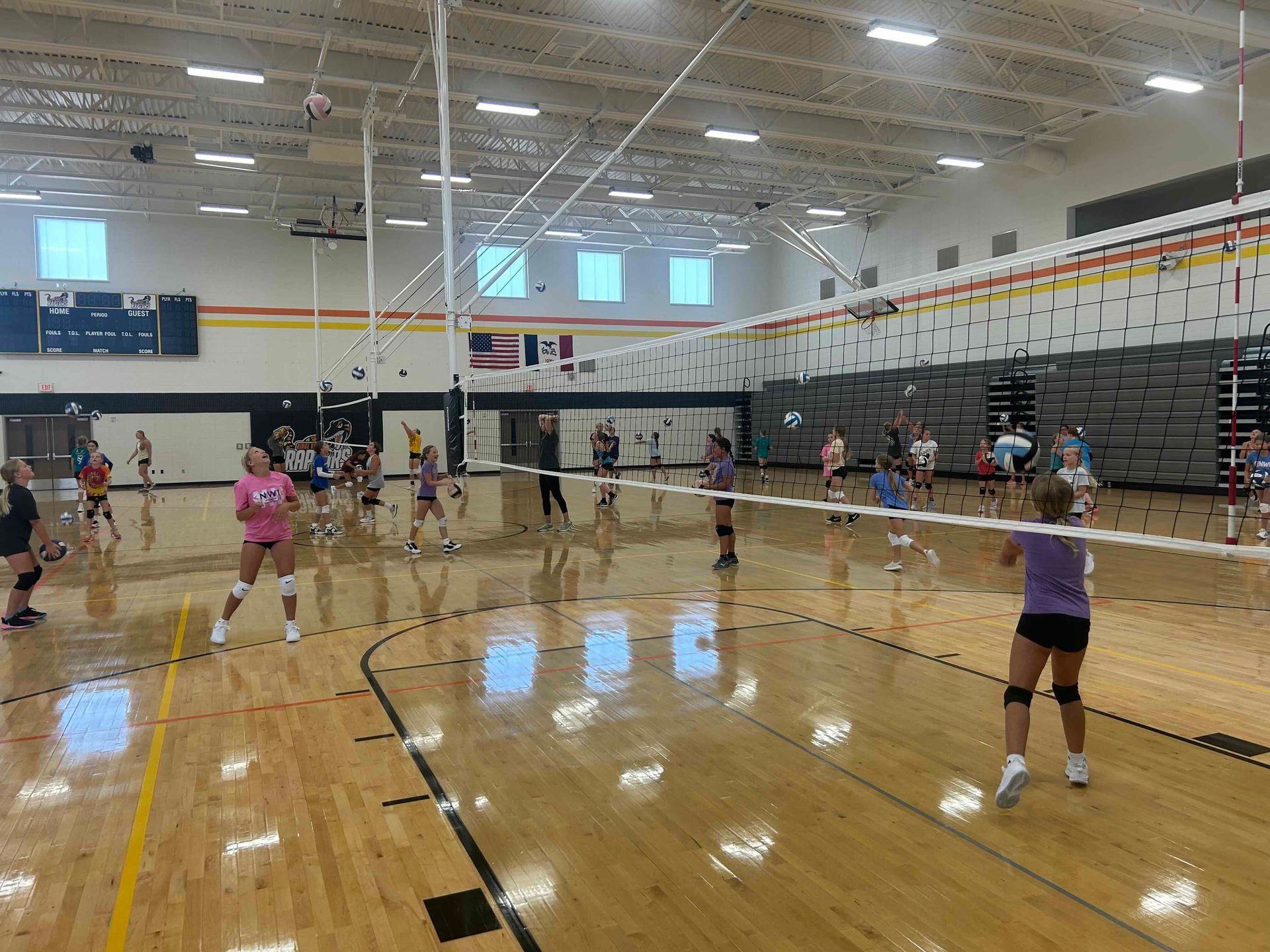 A group of people are standing on a wooden floor in a gym.