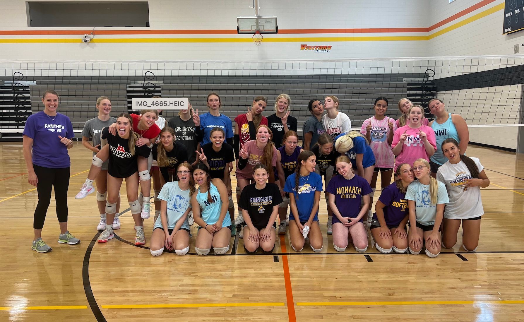 A group of volleyball players are posing for a picture in a gym.