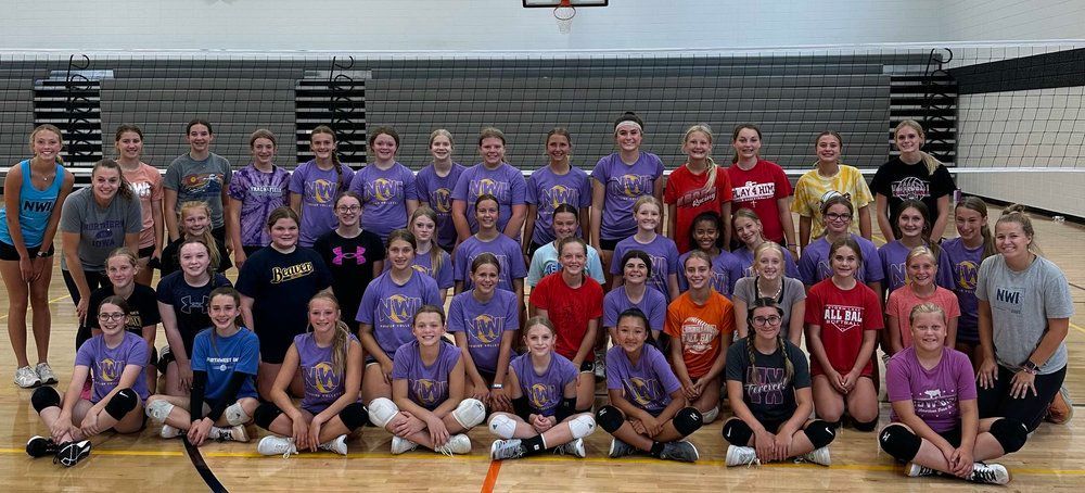 A group of volleyball players are posing for a picture in a gym.