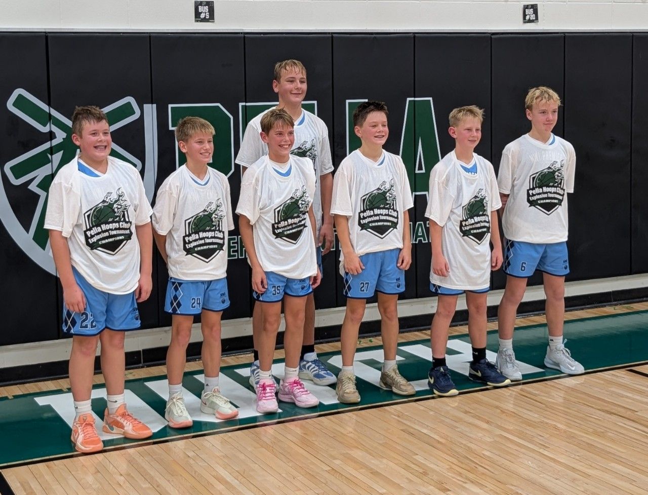 A group of volleyball players are posing for a picture in a gym.
