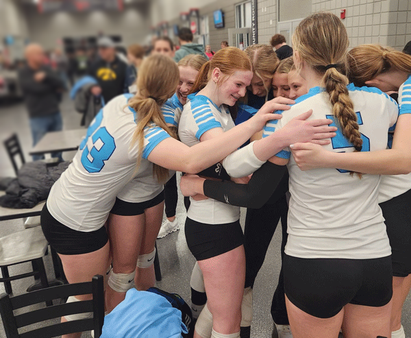 A group of female volleyball players are hugging each other