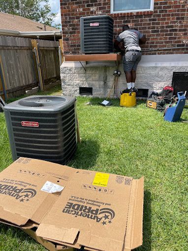 A man is working on an air conditioner in the backyard of a house.
