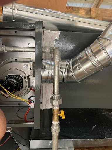 A person is working on a gas heater with a yellow valve.