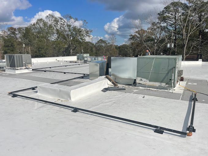 A white roof with a lot of air conditioners on it.