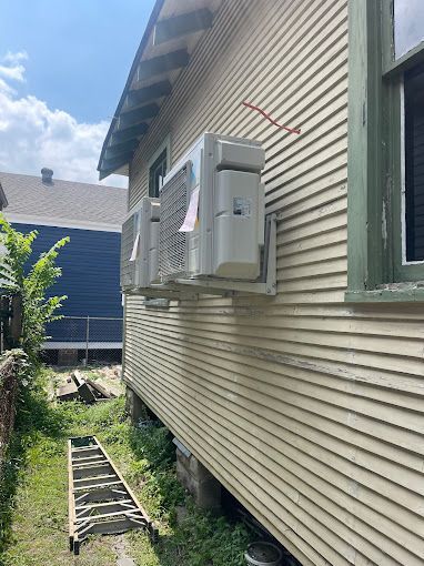 A house with a lot of air conditioners on the side of it.