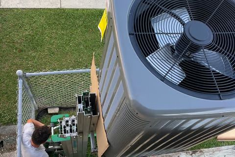 A man is standing next to a large air conditioner.