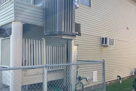 A bicycle is parked in front of a building next to a chain link fence.