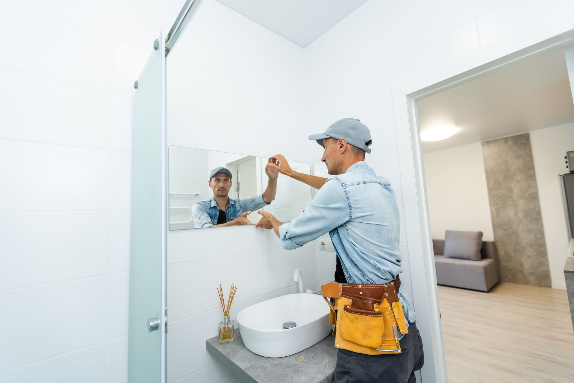 Mirror installation technician mounting a bathroom mirror above the sink