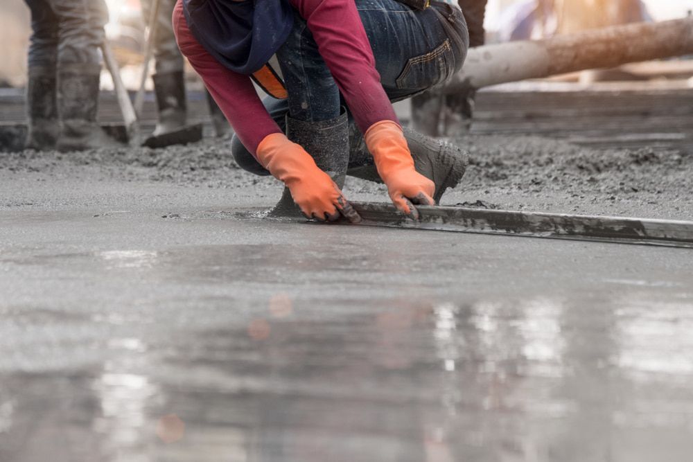 A Construction Worker is Kneeling Down to Spread Concrete on the Ground — Aussie Mad Pumping In Gympie, QLD
