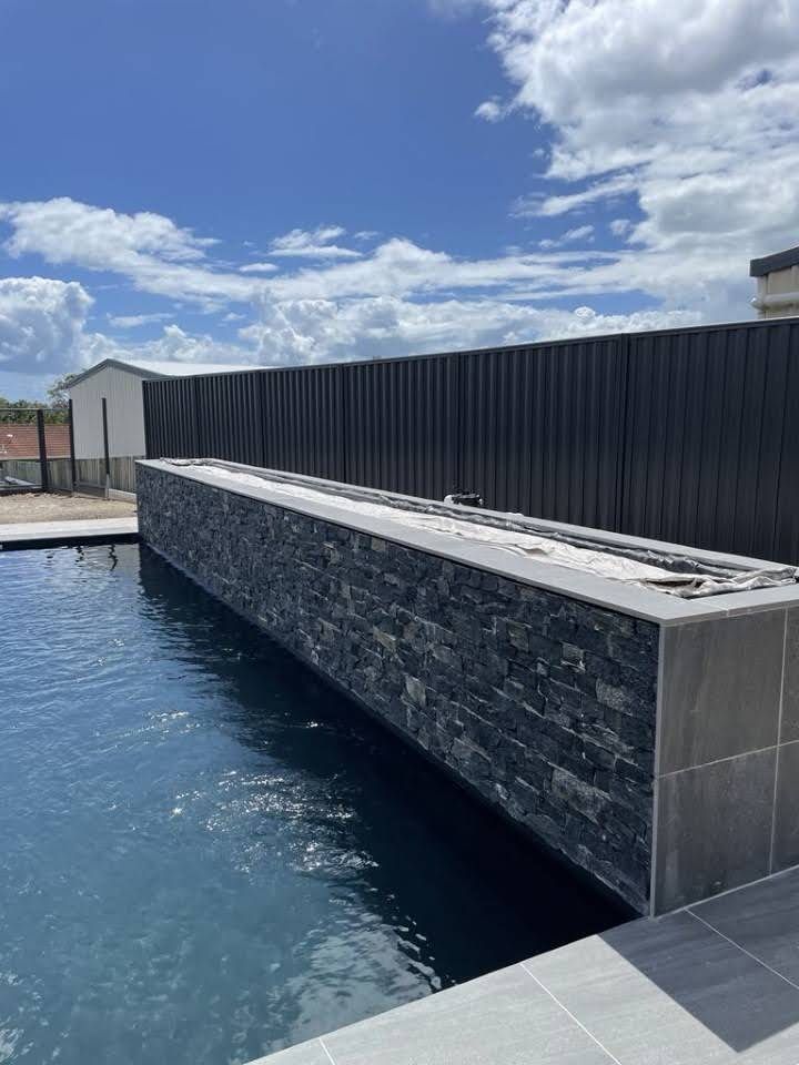 A Large Swimming Pool With a Black Fence Surrounding It — Aussie Mad Pumping In Wondunna, QLD