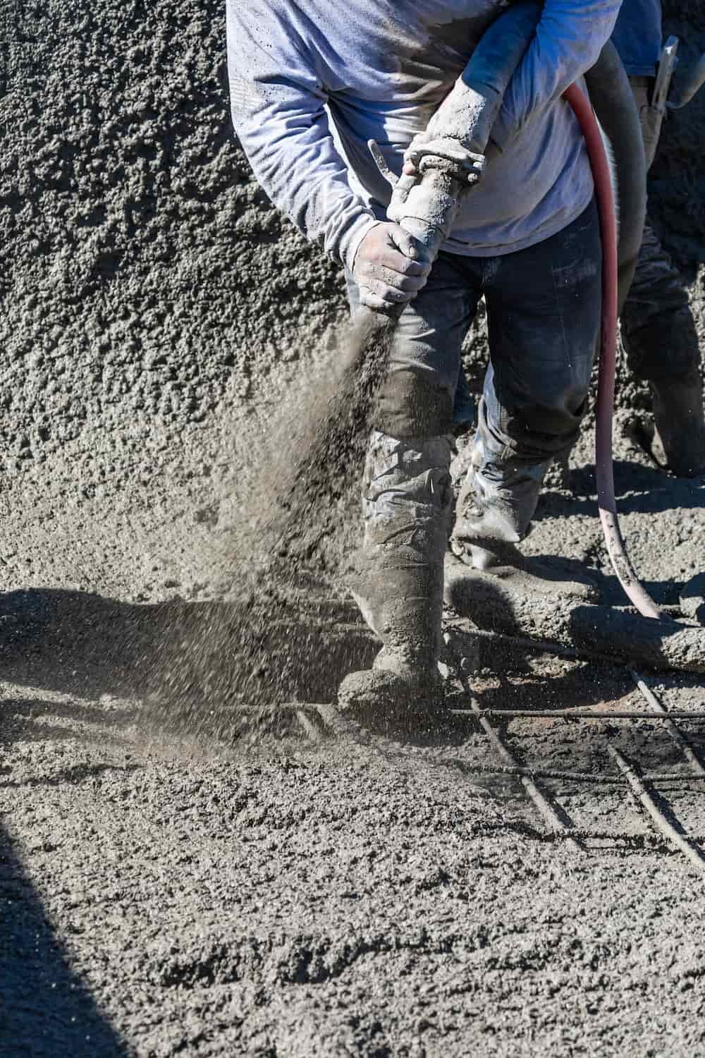 A Man is Pouring Concrete With a Hose on a Construction Site — Aussie Mad Pumping In Wondunna, QLD