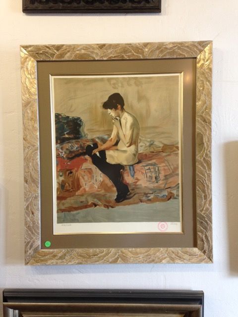 A framed painting of a woman sitting on a rug