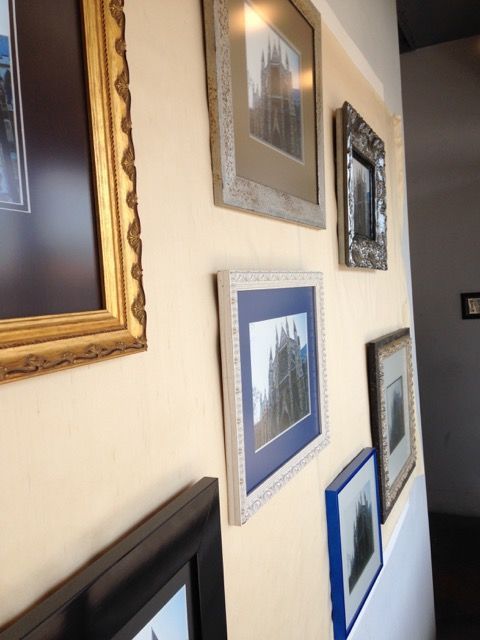 A row of framed pictures are hanging on a wall left view