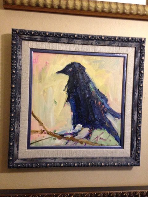 A framed painting of a black bird sitting on a branch