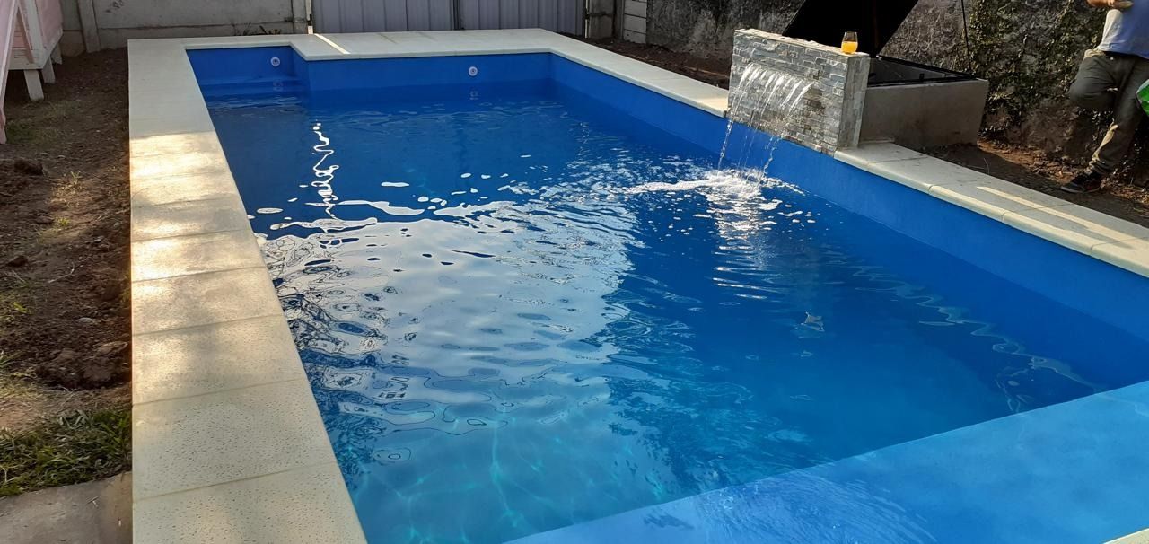 Una piscina rectangular con agua azul y una pequeña cascada.