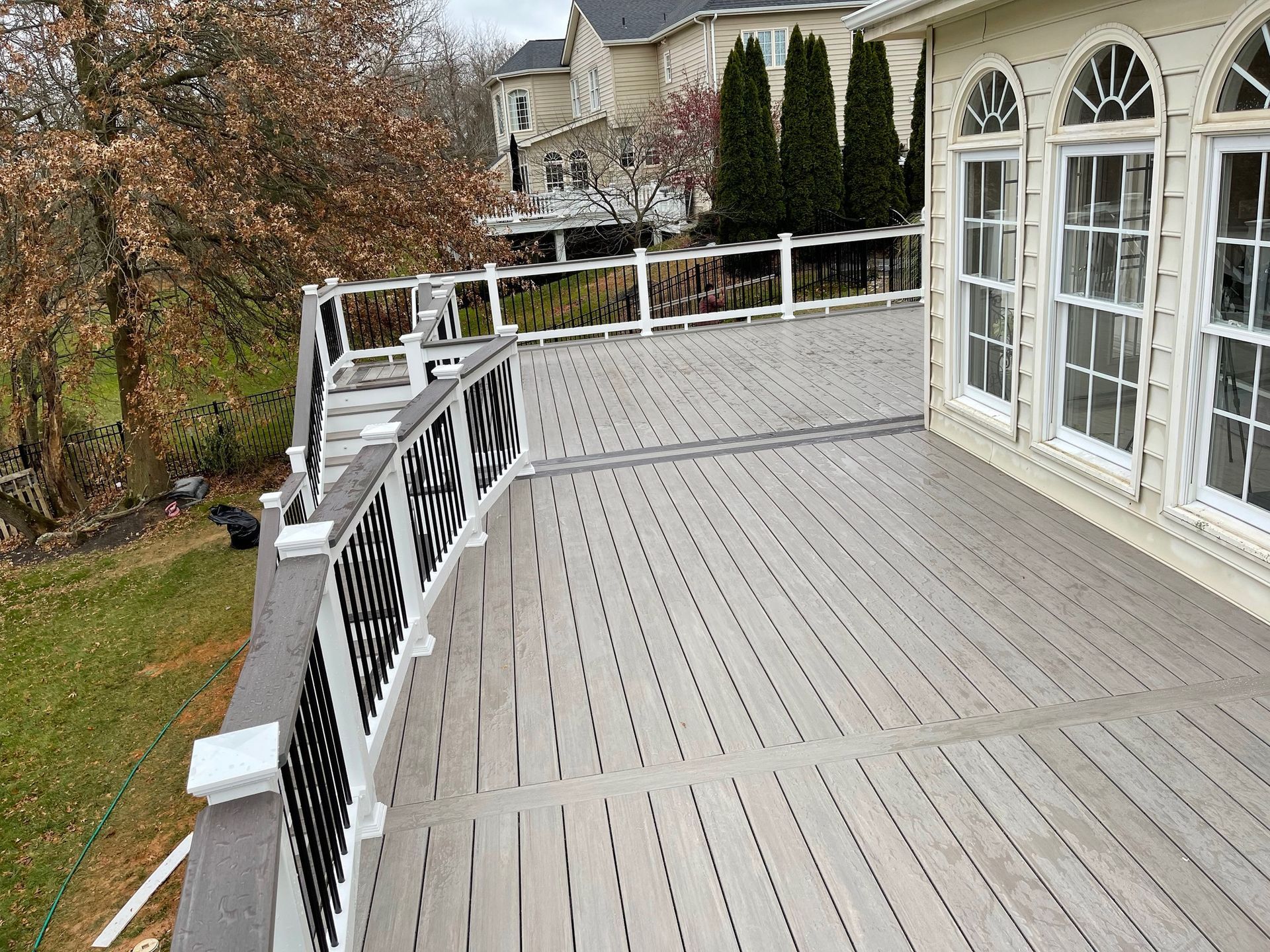 A large deck with a white railing and a lot of windows.