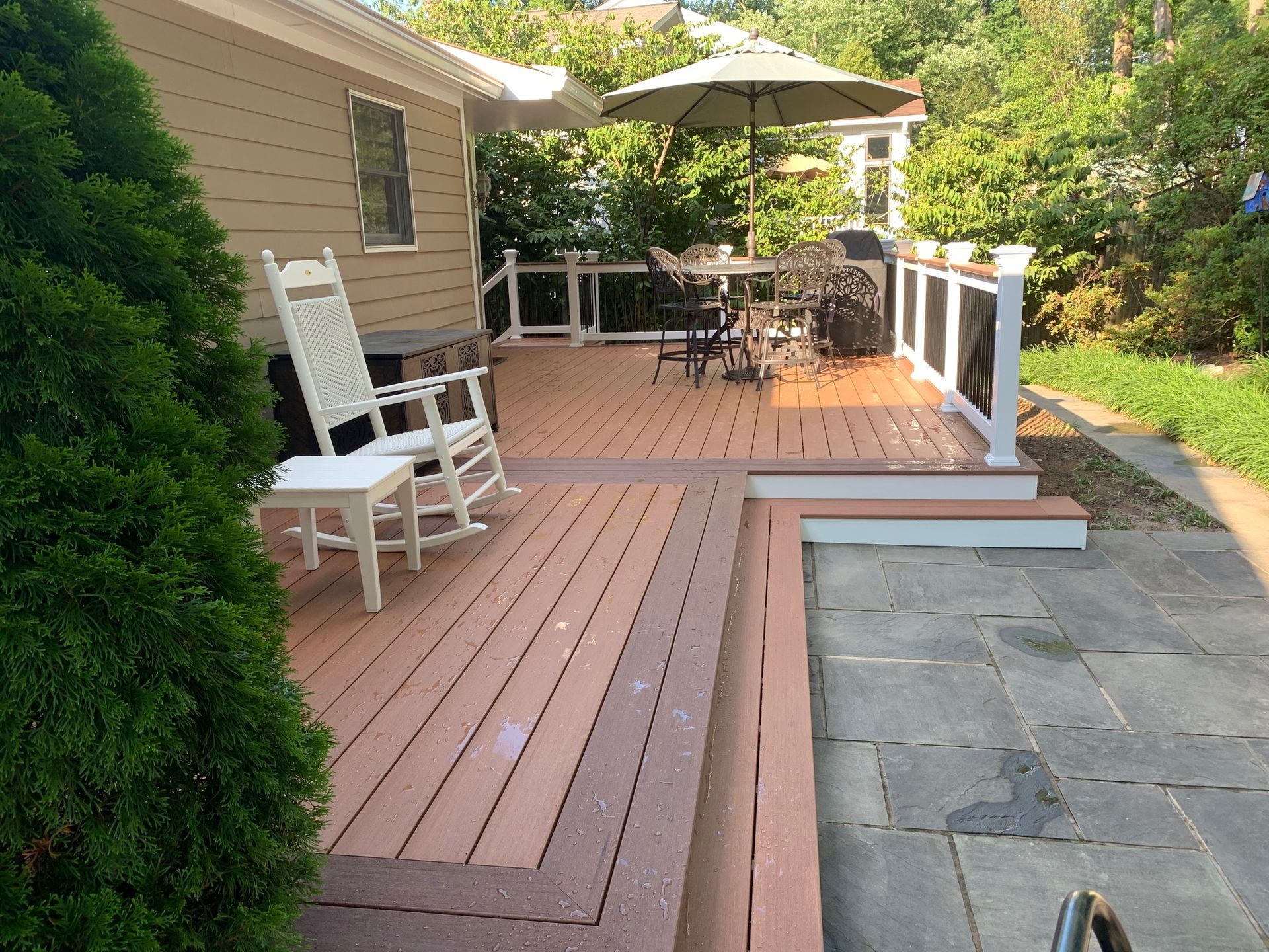 A wooden deck with rocking chairs and an umbrella