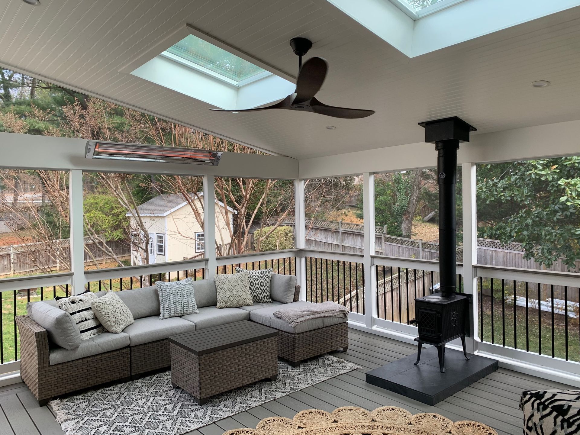 A screened in porch with a couch and a ceiling fan