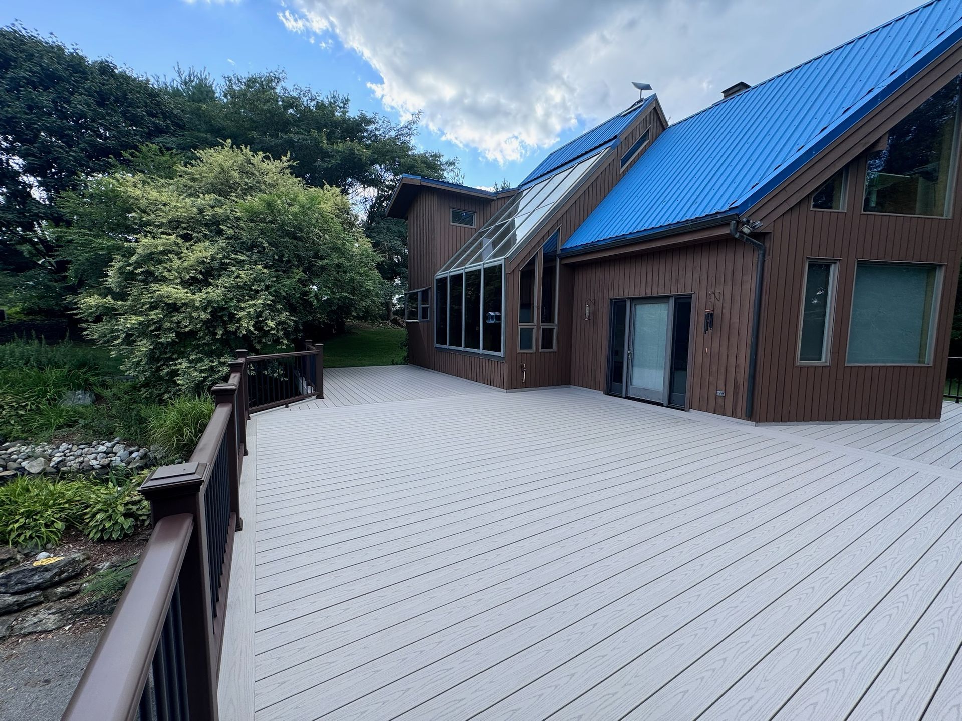 A large house with a blue roof and a large deck