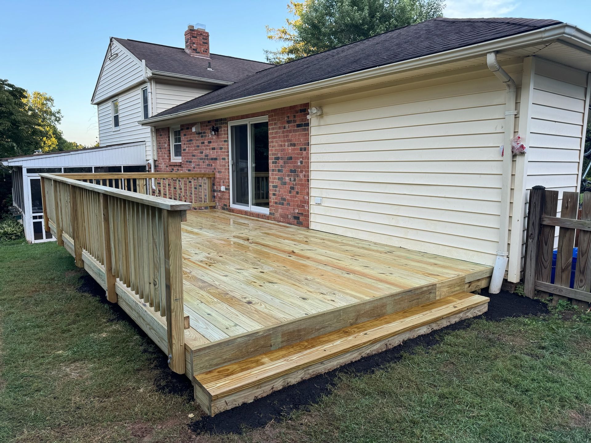 A wooden deck is being built in the backyard of a house.