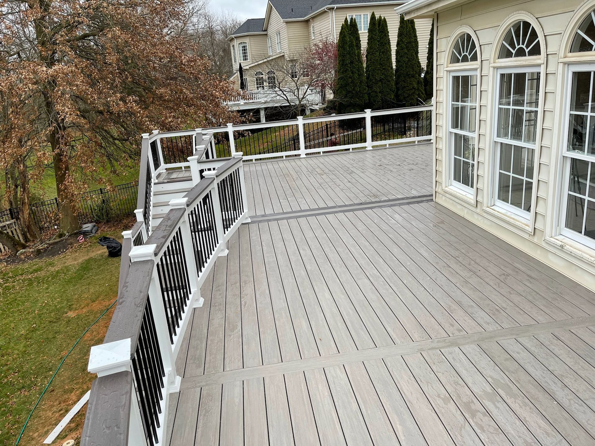 There is a large deck with a railing and a lot of windows.