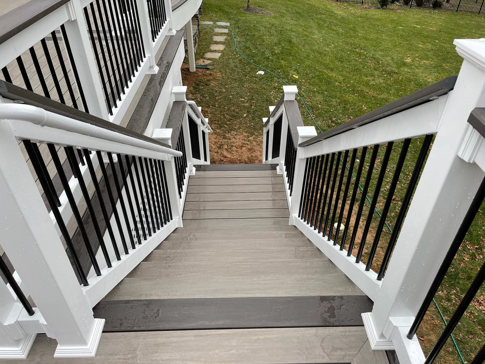 A set of stairs leading up to a deck with a black railing.