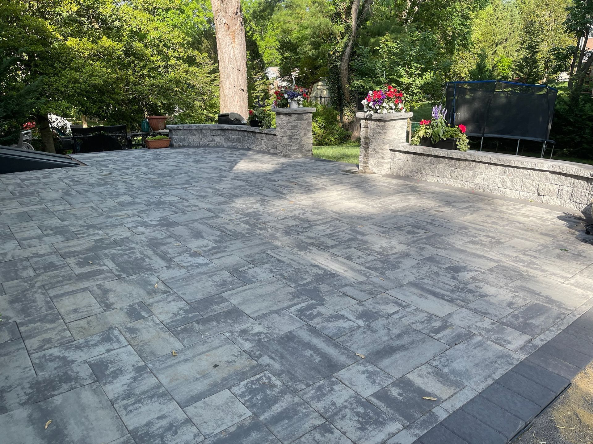 A patio with a stone wall and a bench in a park.