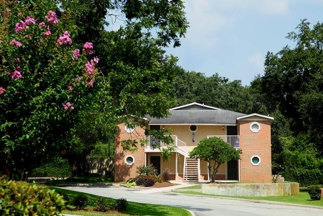 A brick apartment building with pink flowers in front of it