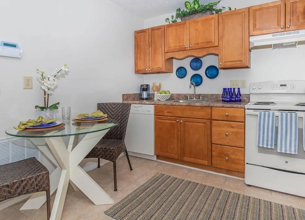 A kitchen with wooden cabinets , white appliances , a table and chairs.