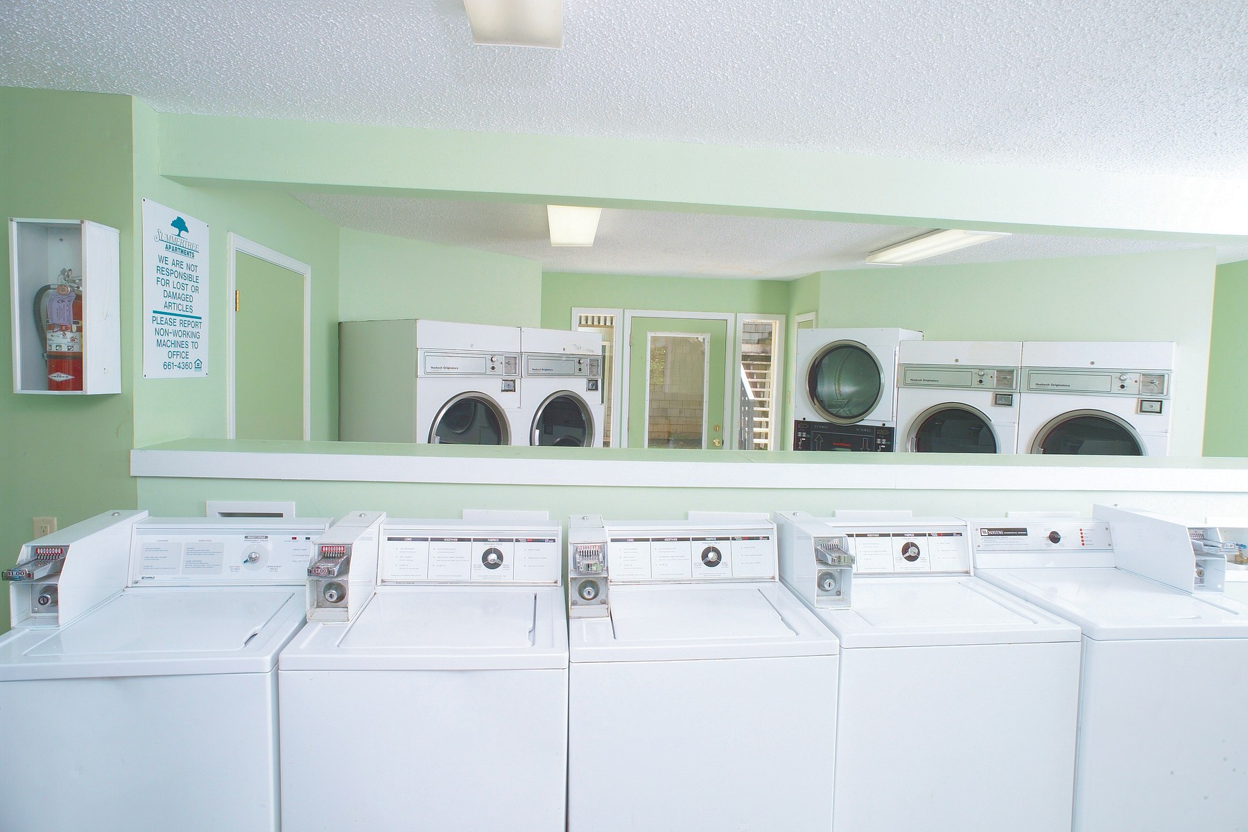 A row of white washers and dryers in a laundromat.