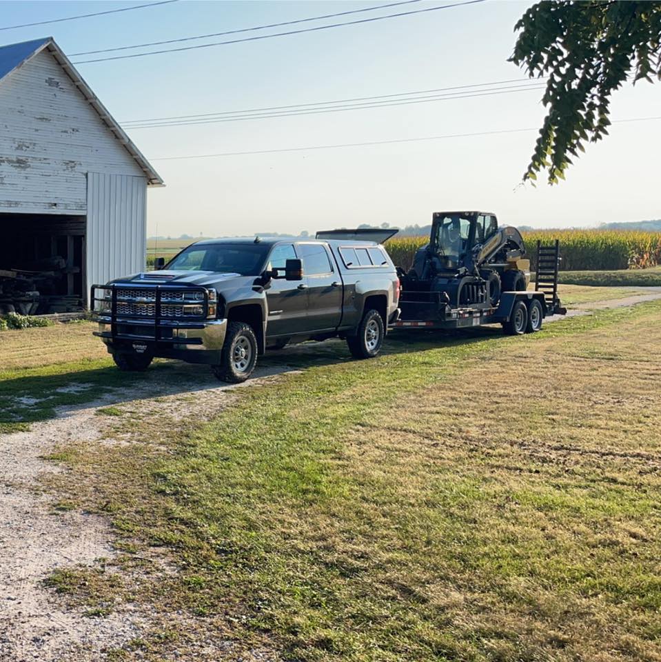 A truck is pulling a trailer with a tractor on it.